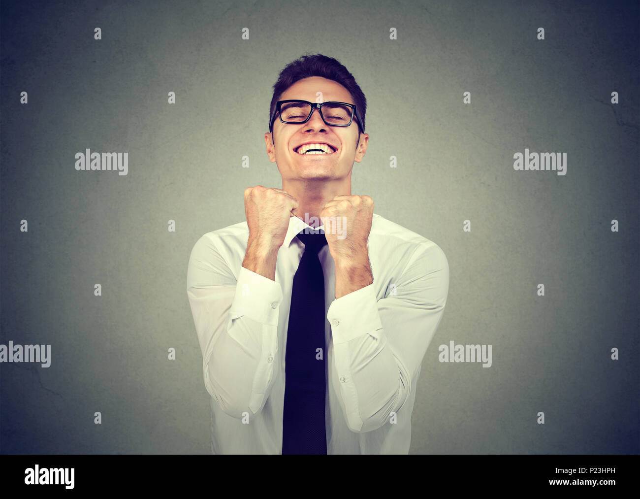 Successful business man with fists pumped celebrating success isolated on grey background. Positive human emotion facial expression. Stock Photo