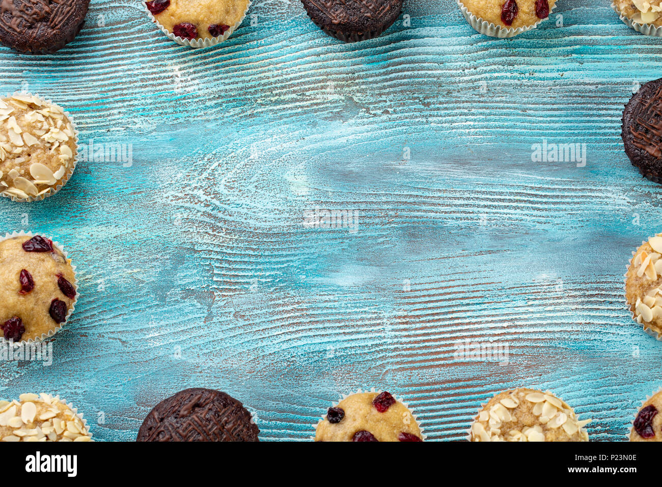 Homemade chocolate chip muffins as a frame on blue wooden table. Copy space Stock Photo