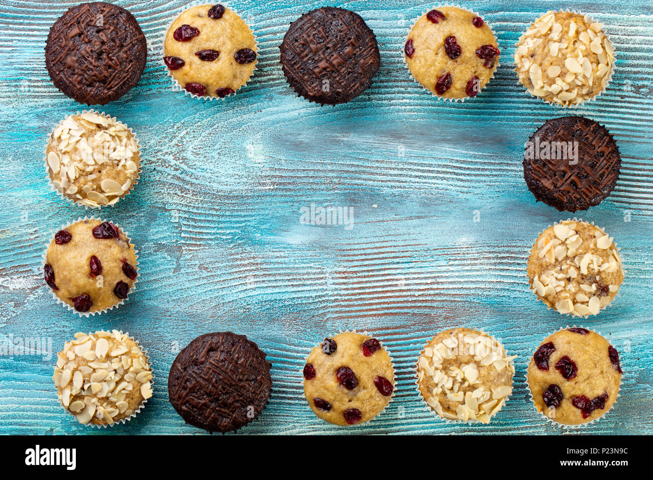 Homemade chocolate chip muffins as a frame on blue wooden table. Copy space Stock Photo