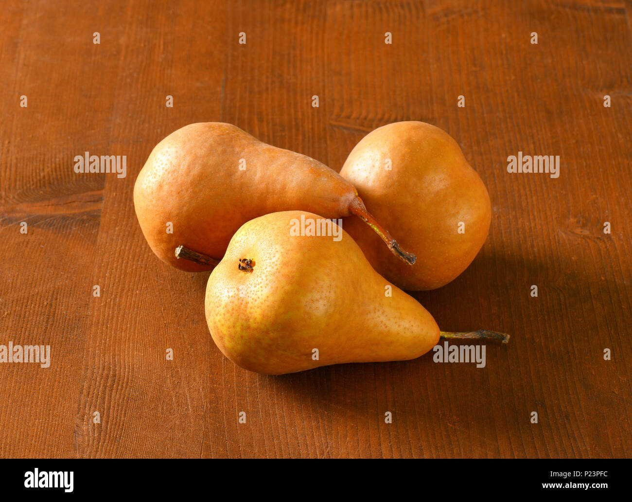 three ripe bosc pears on wooden table Stock Photo