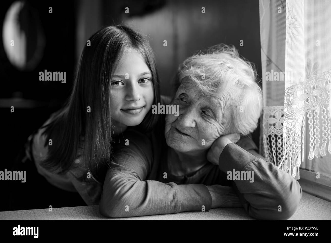 A little girl hugs her grandmother. Black and white portrait. Stock Photo
