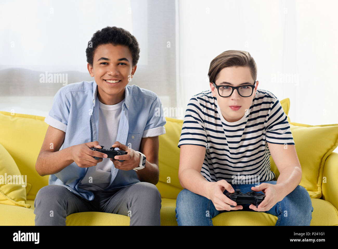 Excited multiethnic teen friends enjoying video games, free time at home, Stock image