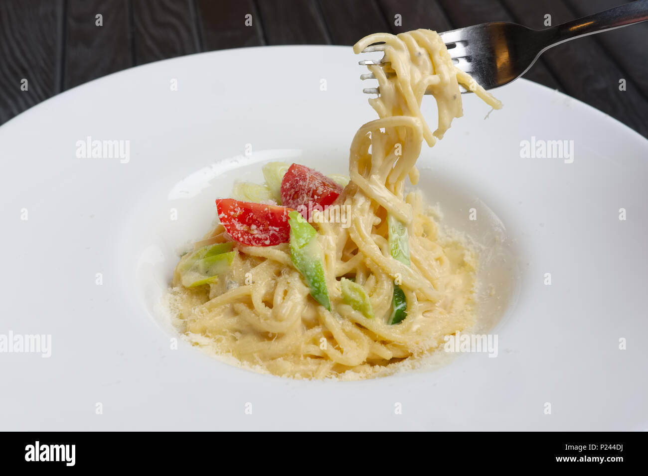 Plate with pasta served with bacon and ham, decorated with tomato cherry Stock Photo