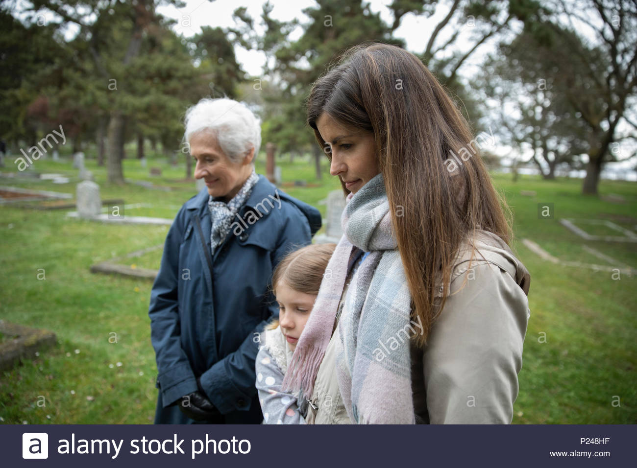 Multi-generation women visiting gravesite at cemetery Stock Photo