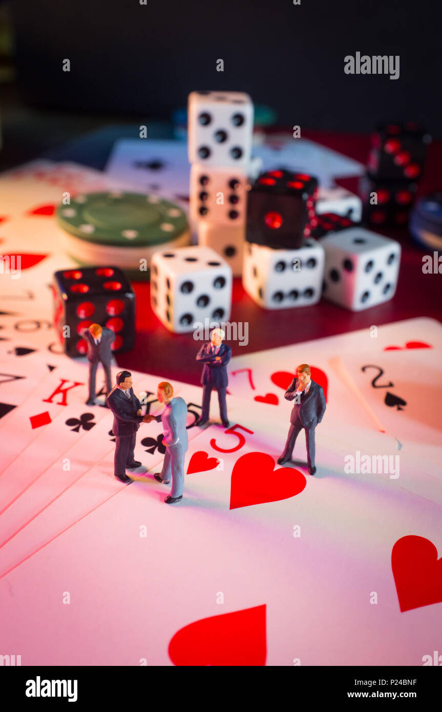 Miniature businessmen figurines making a deal on casino gambling card ...