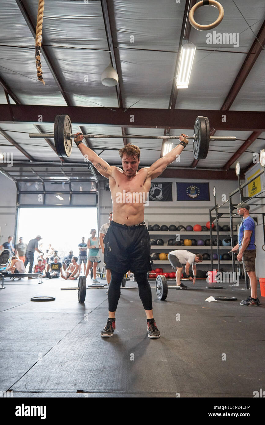 Male or man competing in a CrossFit fitness challenge competition by dead lifting weights inside a gym in Montgomery Alabama, USA. Stock Photo