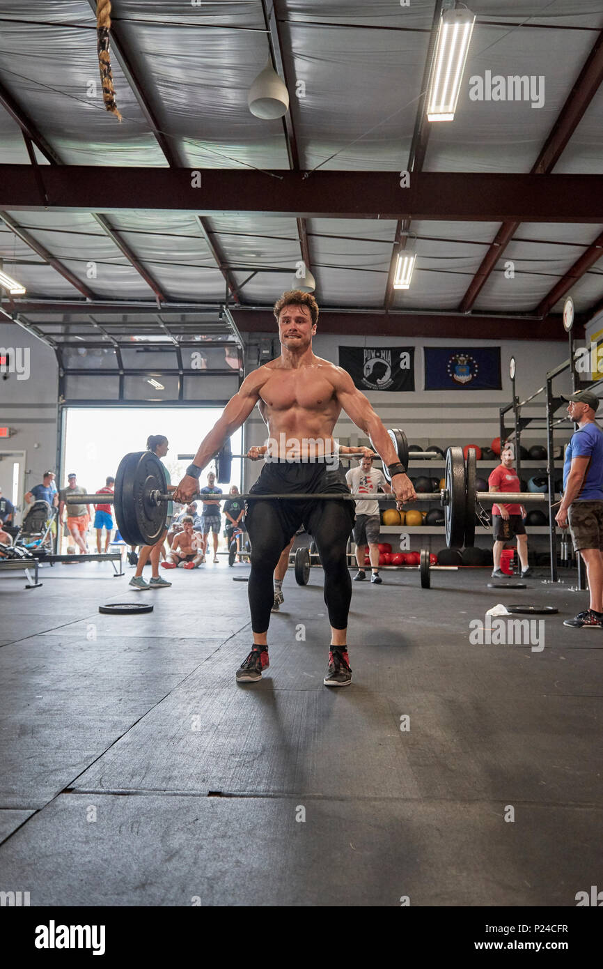 Male or man competing in a CrossFit fitness challenge competition by dead lifting weights inside a gym in Montgomery Alabama, USA. Stock Photo