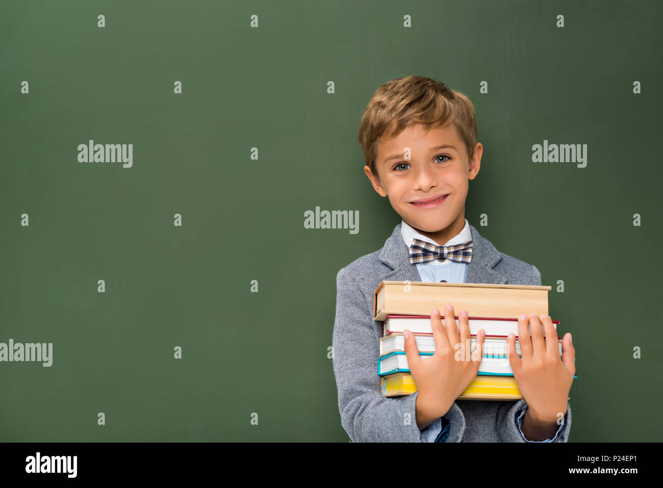 smiling schoolboy with stack of books next to chalkboard Stock Photo ...