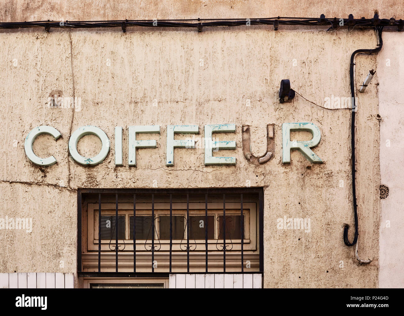 Lettering 'Coiffeur', old and decayed on a wall of a house, a letter is missing Stock Photo