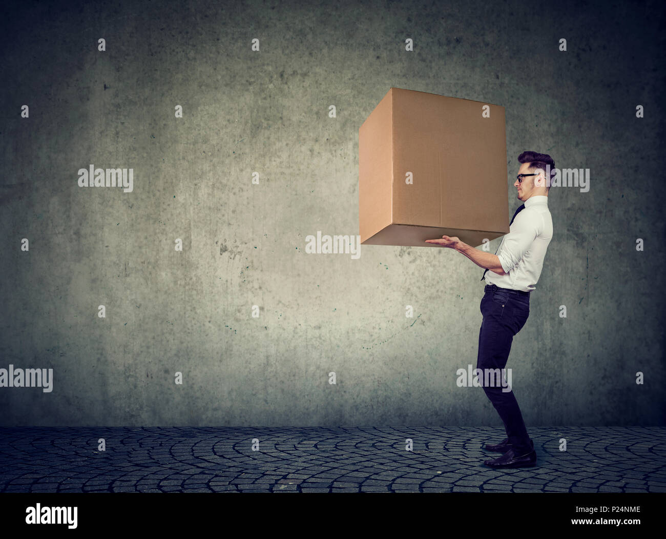 Side view of casual man lifting heavy box working in shipping company and delivering package. Stock Photo