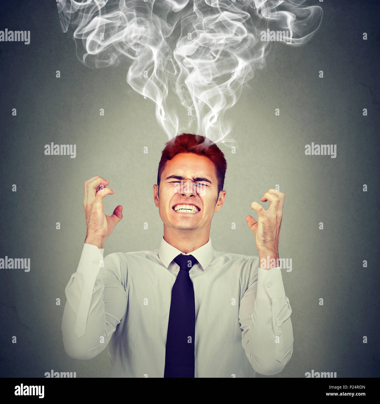 Stressed business man having headache steam coming up isolated on gray wall background Stock Photo