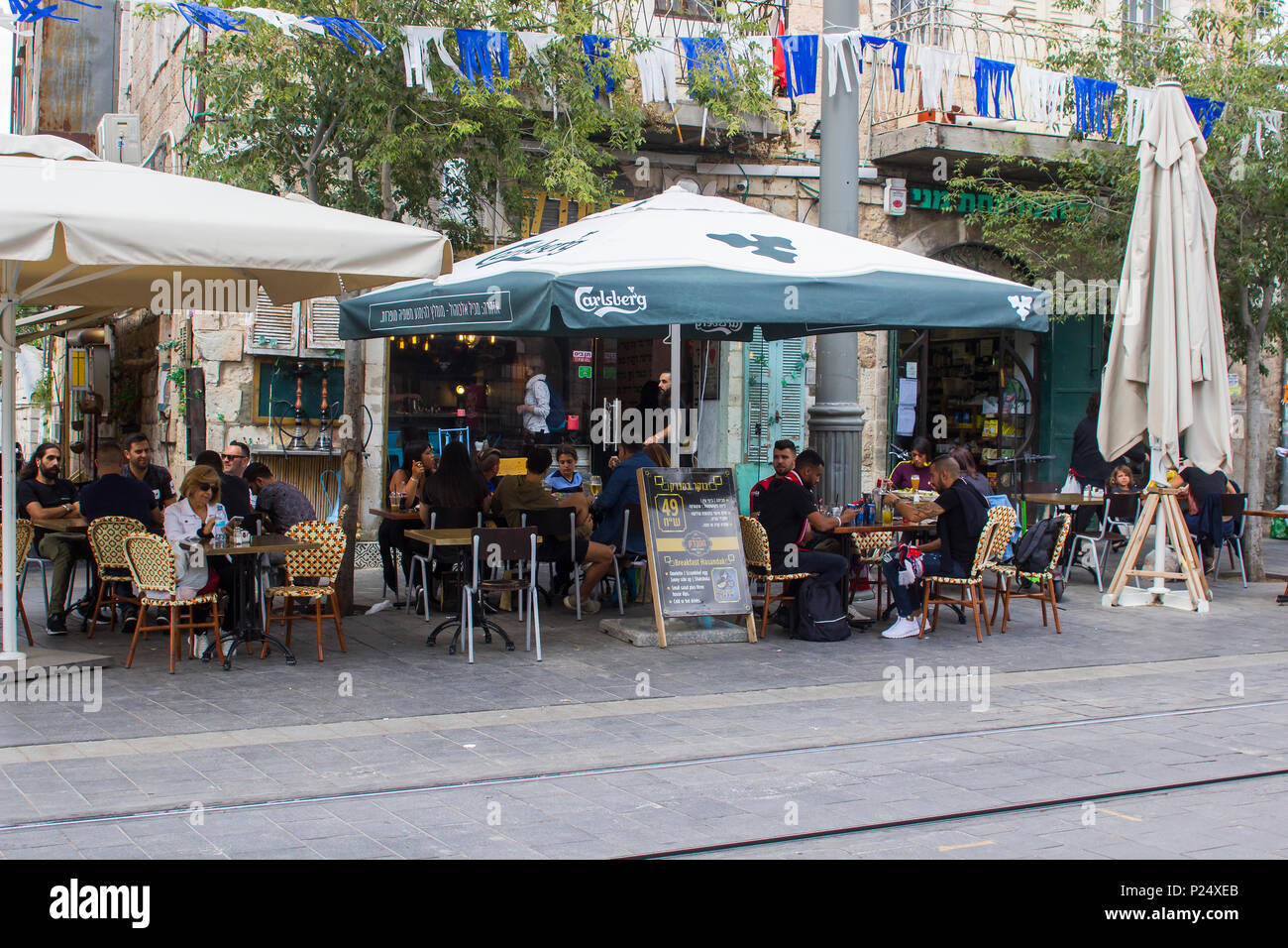 9 May 2018 Customers relaxing and talking while  sitting at tables in a street cafe on Jaffa Street in Jerusalem Israel Stock Photo