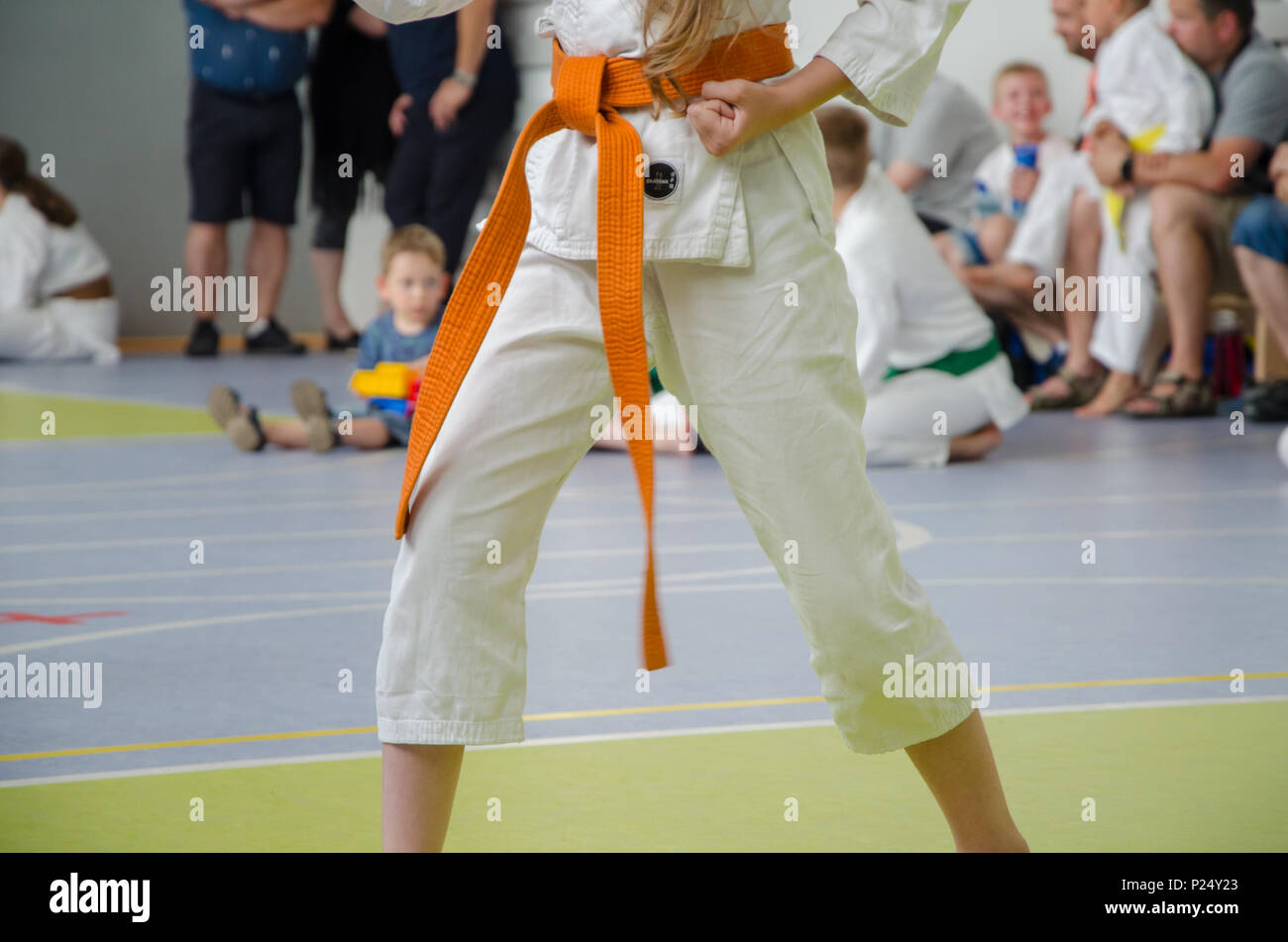 karate competition. a girl in kimono with orange belt. no face. the hand is compressed in a fist Stock Photo