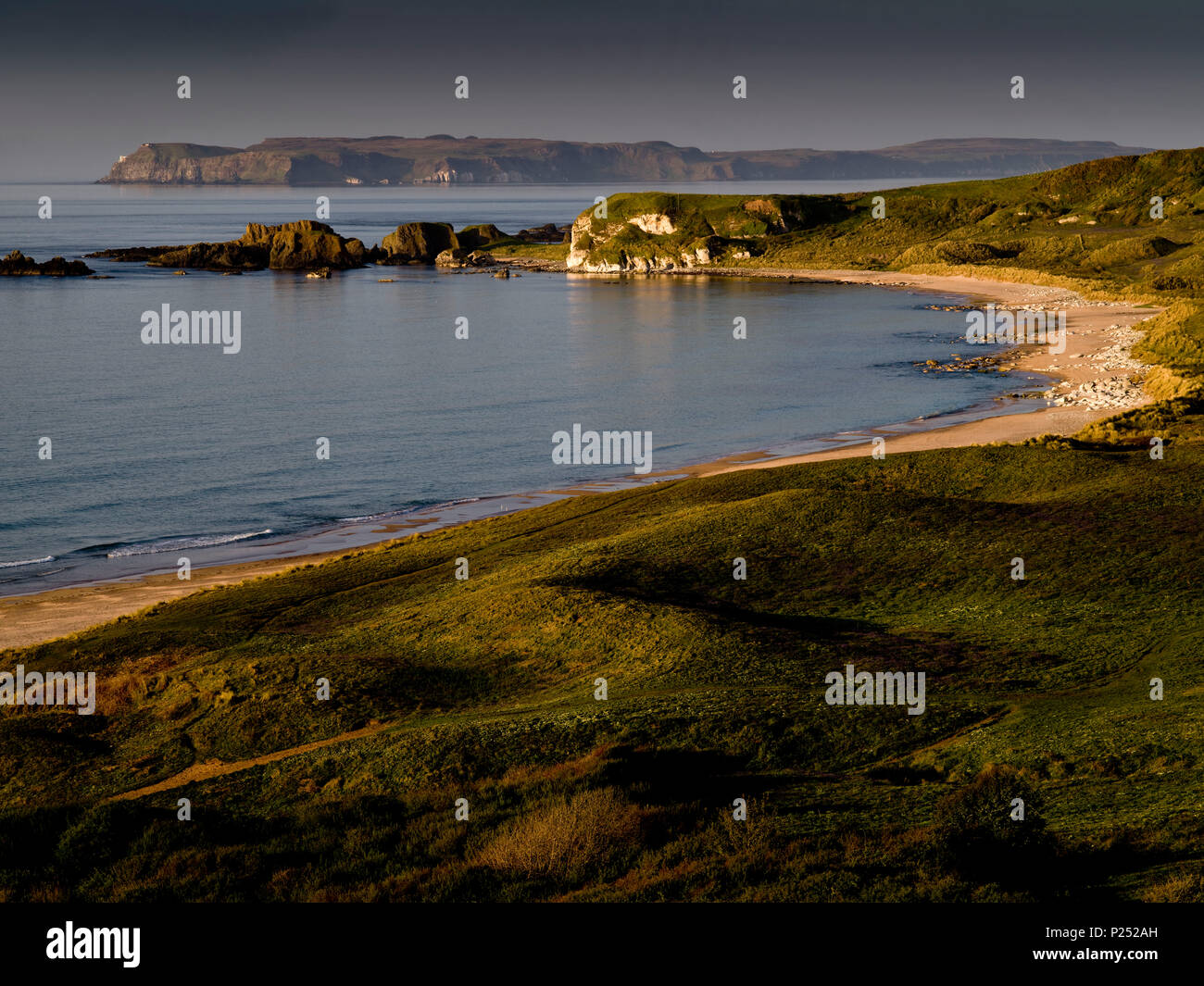 Northern Ireland, Antrim, Causeway Coast, sandy beach with basalt and mussel limestone rock in the White Park Bay, view to Rathlin Iceland, Stock Photo