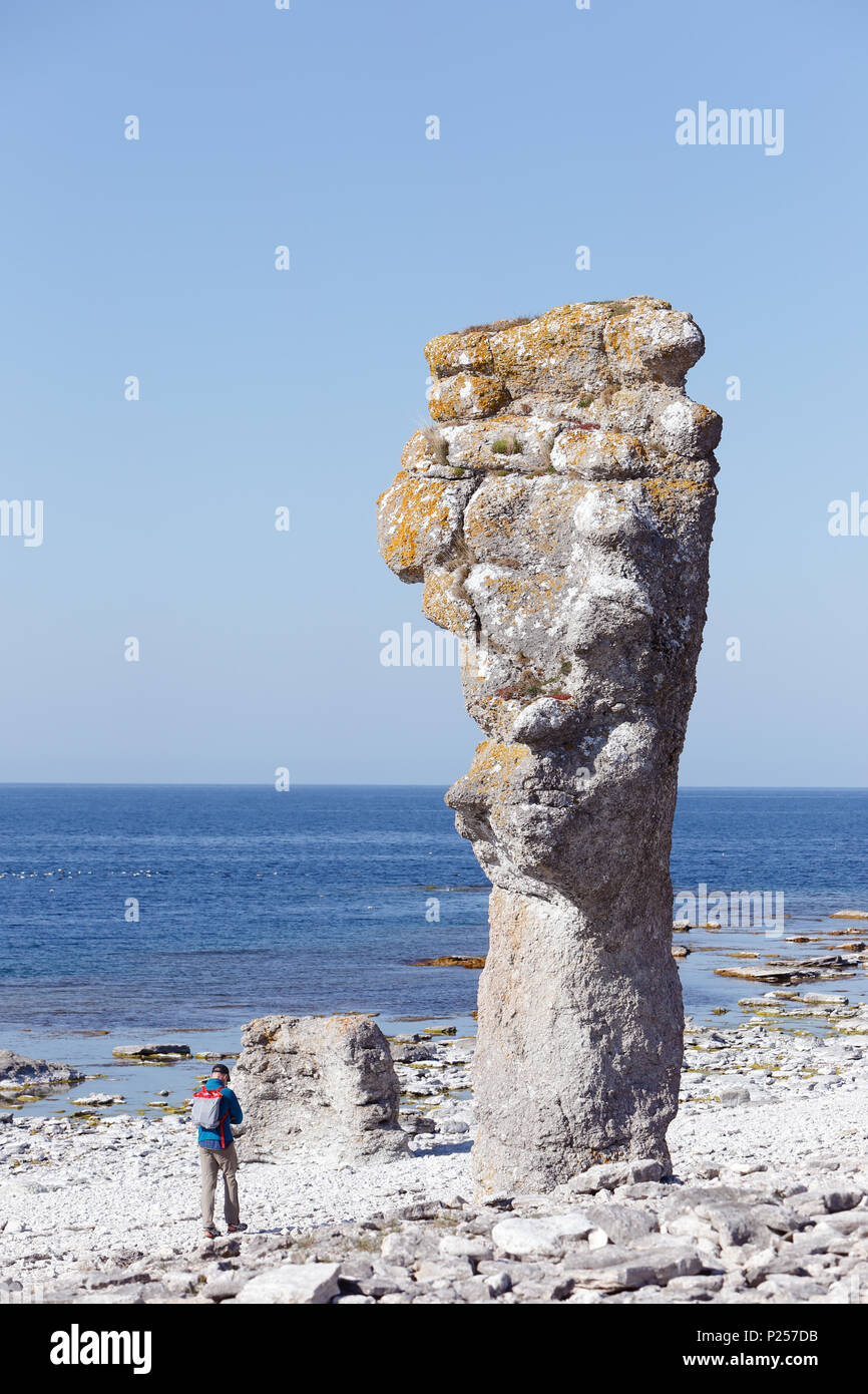 Faro, Sweden -May 13, 2016: A person walking by  the sea stacks at Langhammars on the Faro island in the Swedish province of Gotland. Stock Photo