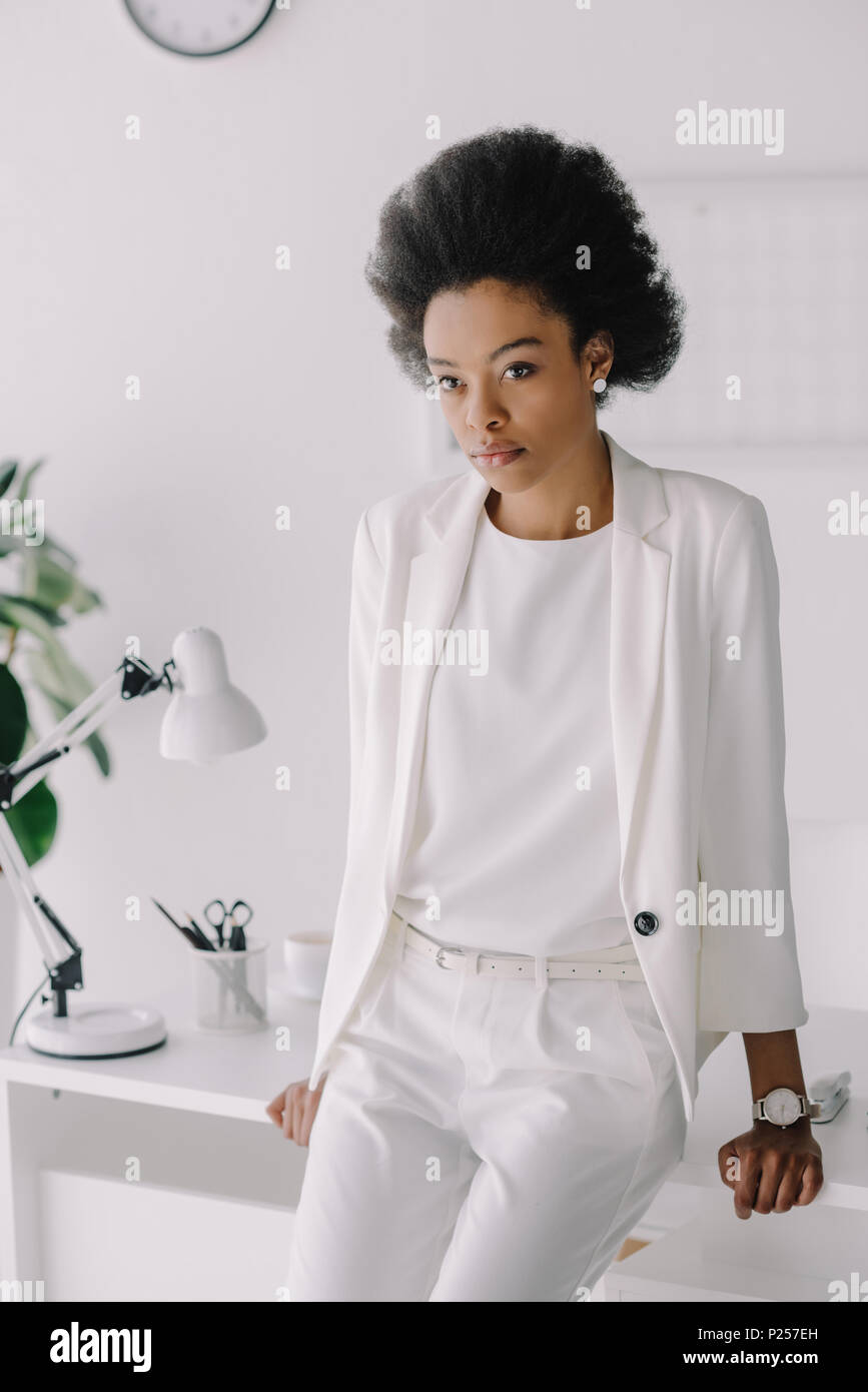 attractive african american businesswoman leaning on table and looking ...