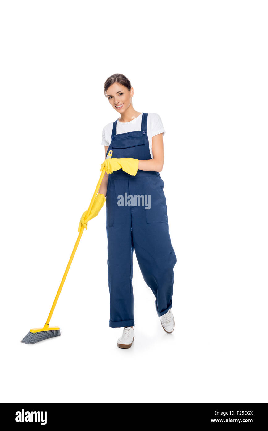 smiling cleaner in uniform with broom in hands looking at camera isolated on white Stock Photo