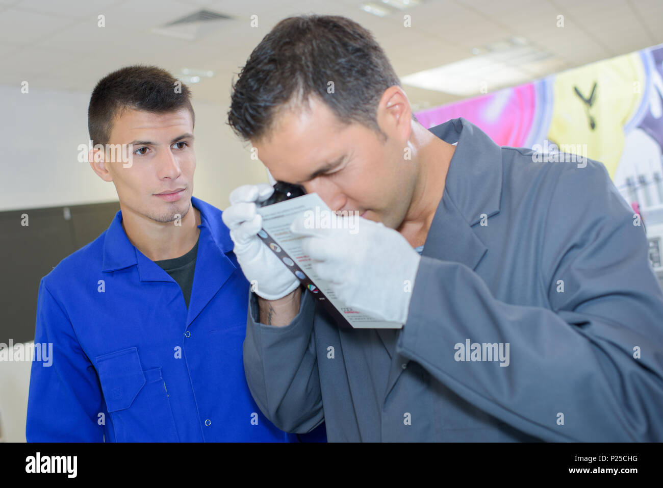 Man looking through eyepiece, apprentice watching Stock Photo