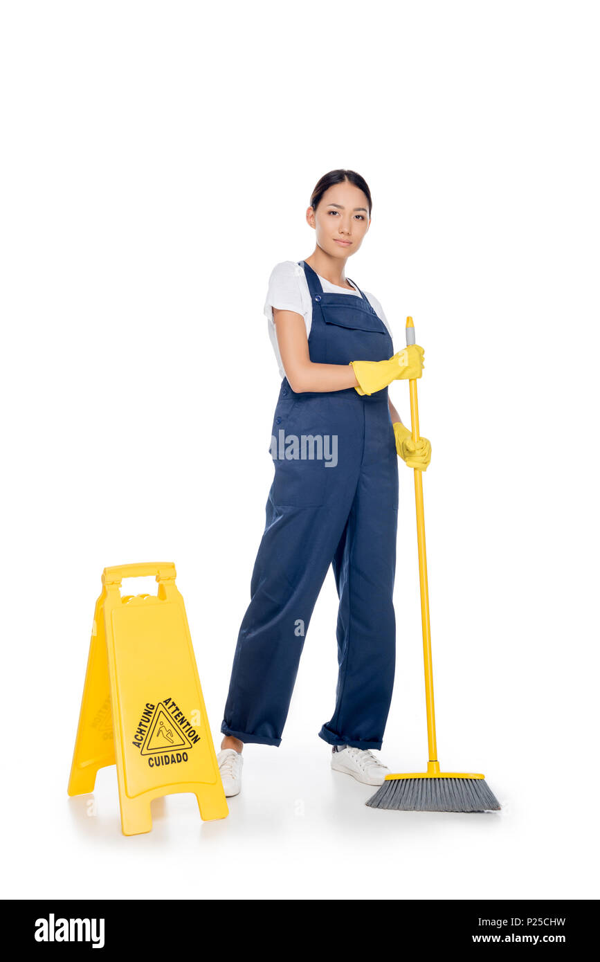 asian cleaner in uniform with broom in hands looking at camera isolated on white Stock Photo
