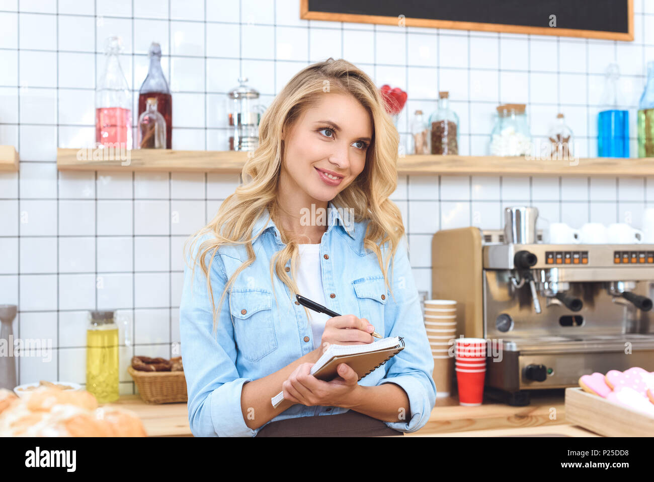 beautiful smiling small business owner taking notes and looking away in ...