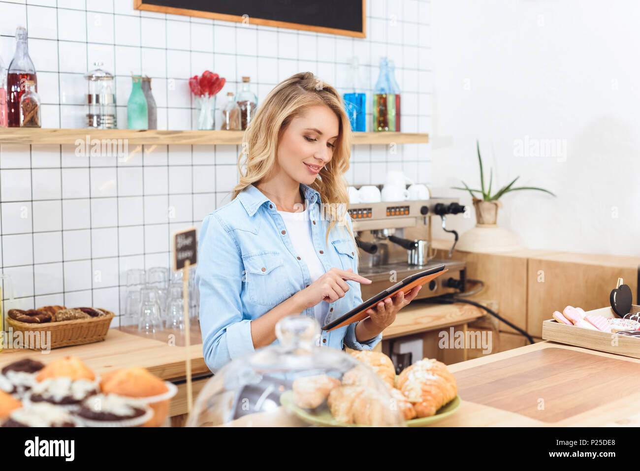 beautiful smiling young waitress using digital tablet in cafe Stock Photo