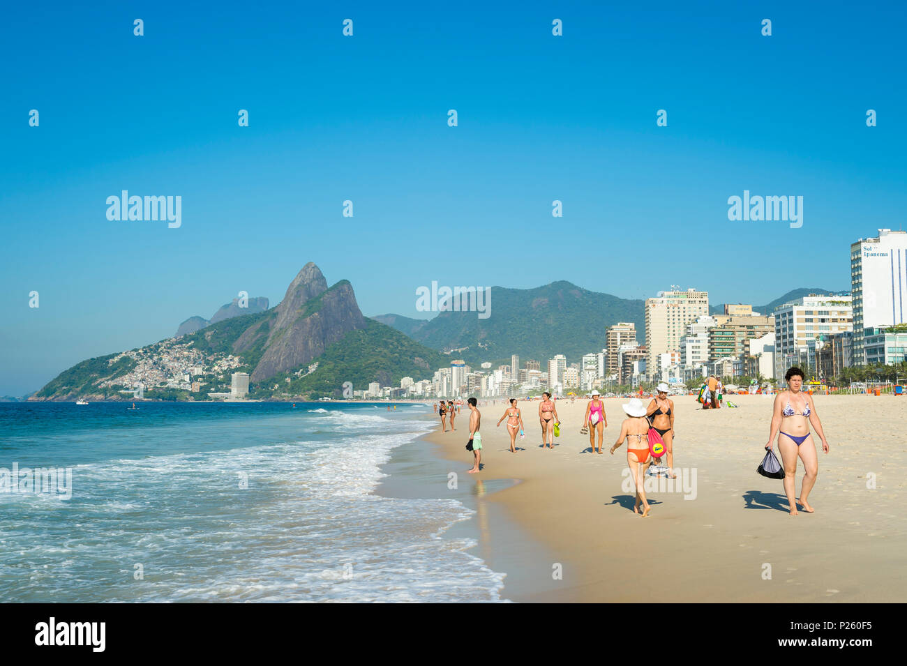 RIO DE JANEIRO - CIRCA JANUARY, 2014: Beachgoers stroll together along Ipanema Beach on a bright summer morning. Stock Photo