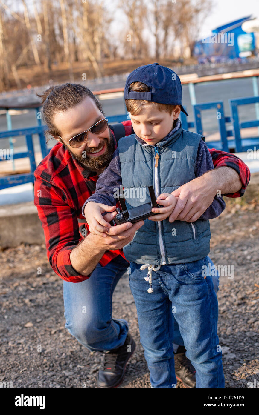 Father and son holding remote control joystick and piloting ...