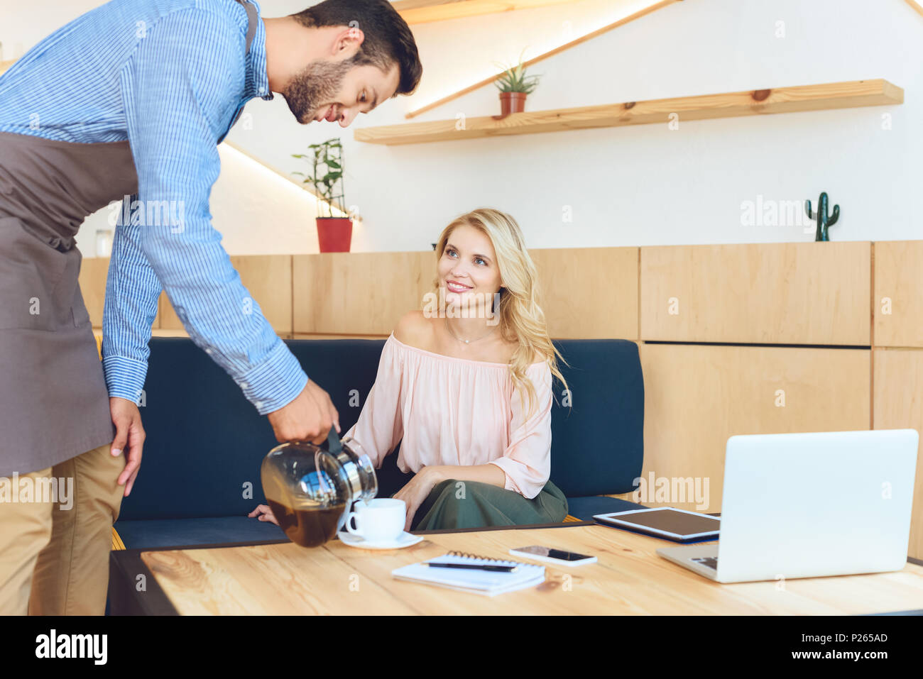 handsome young waiter pouring coffee to beautiful smiling client in ...