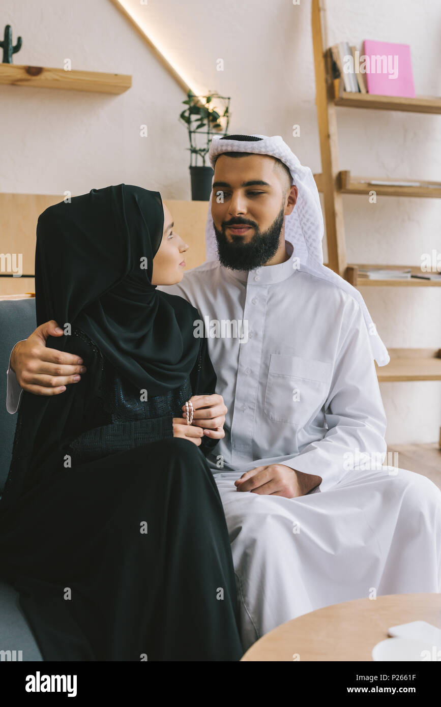 loving muslim couple sitting on sofa and embracing Stock Photo - Alamy