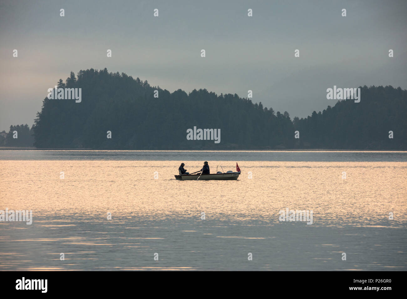 Fishermen in the calm water of Lake Sils at sunrise, Plaun da Lej, canton of Graubunden, Engadine. Switzerland Stock Photo
