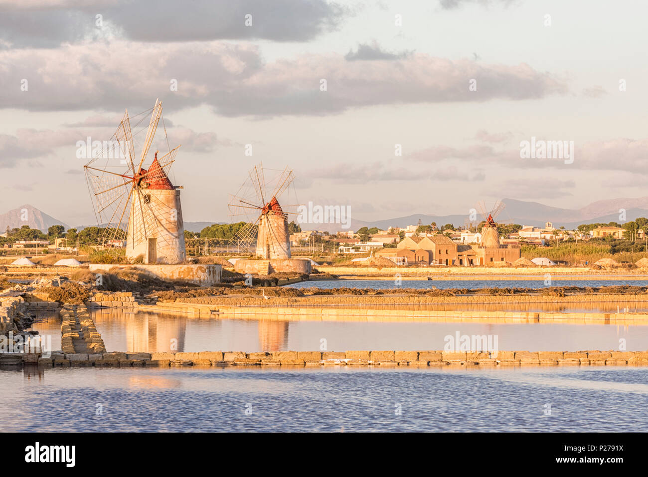 Salt pans with rows of tanks and two fully functional windmills on the coast connecting Marsala to Trapani, Trapani province, Sicily, Italy Stock Photo