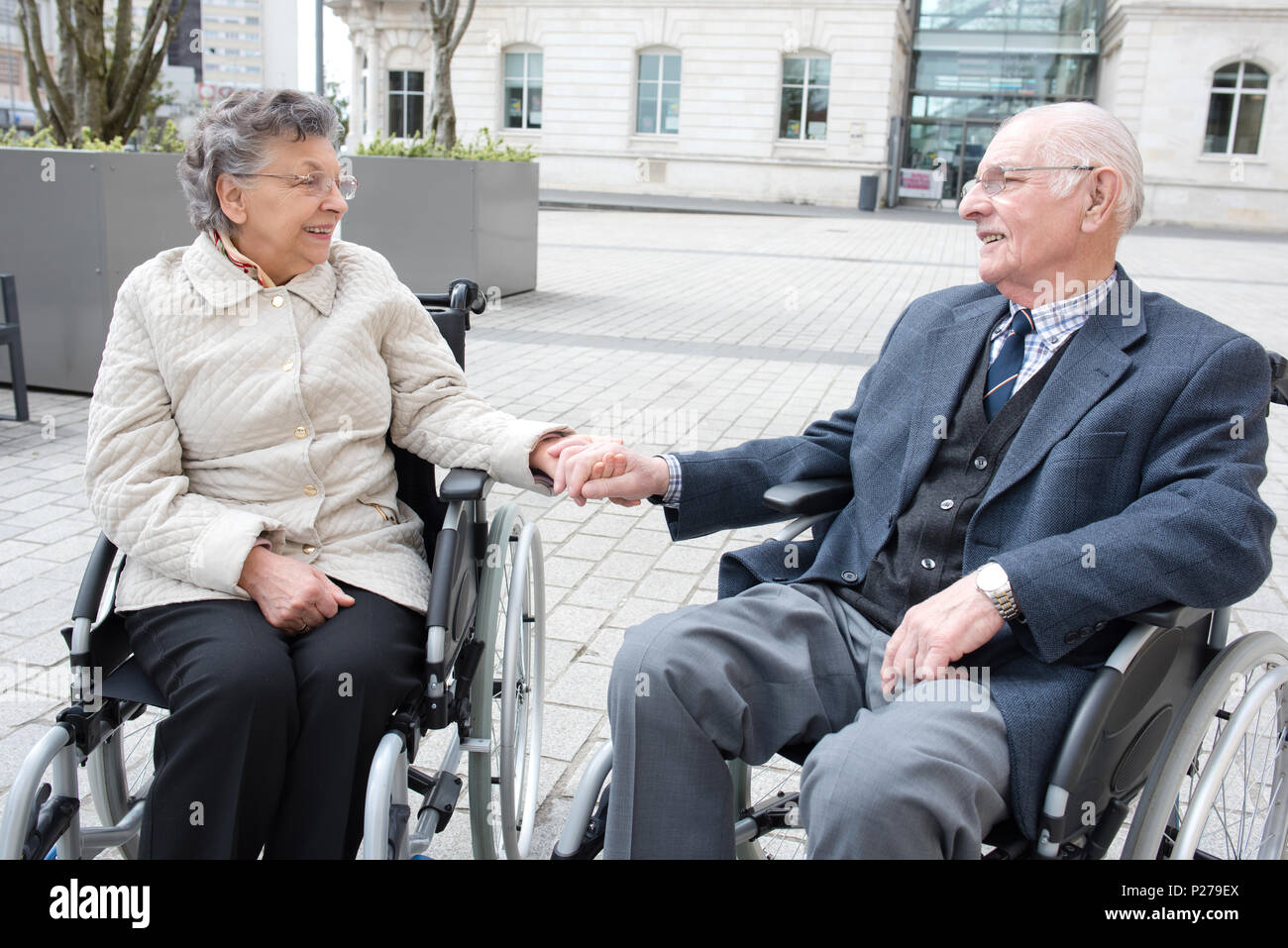 elderly couple in wheelchairs holding hands Stock Photo Alamy