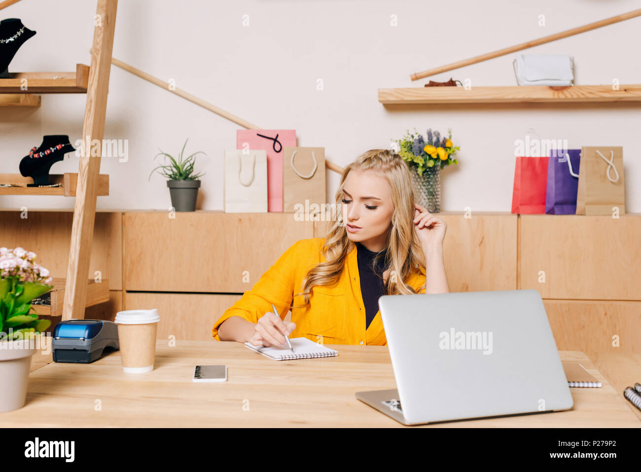 Clothing Store Manager Writing Notes At Workplace Stock Photo