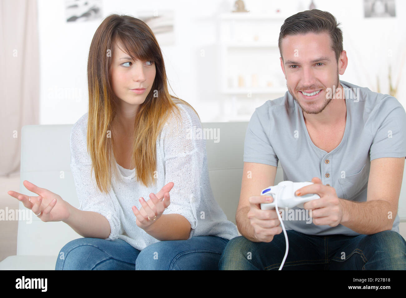 annoyed girlfriend waiting for boyfriend to stop playing videogames Stock Photo Alamy