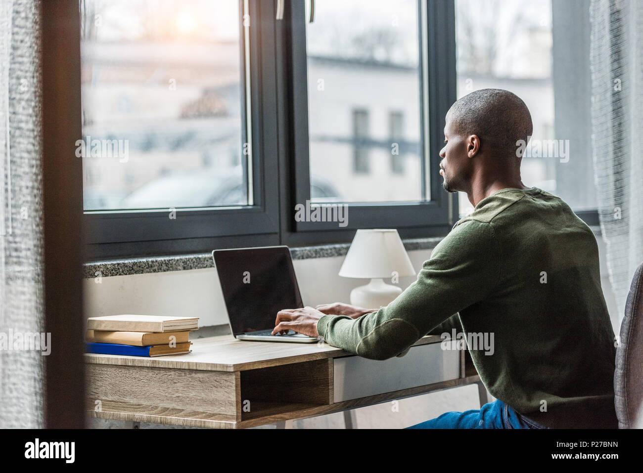 side view of african american man typing on laptop while working at ...