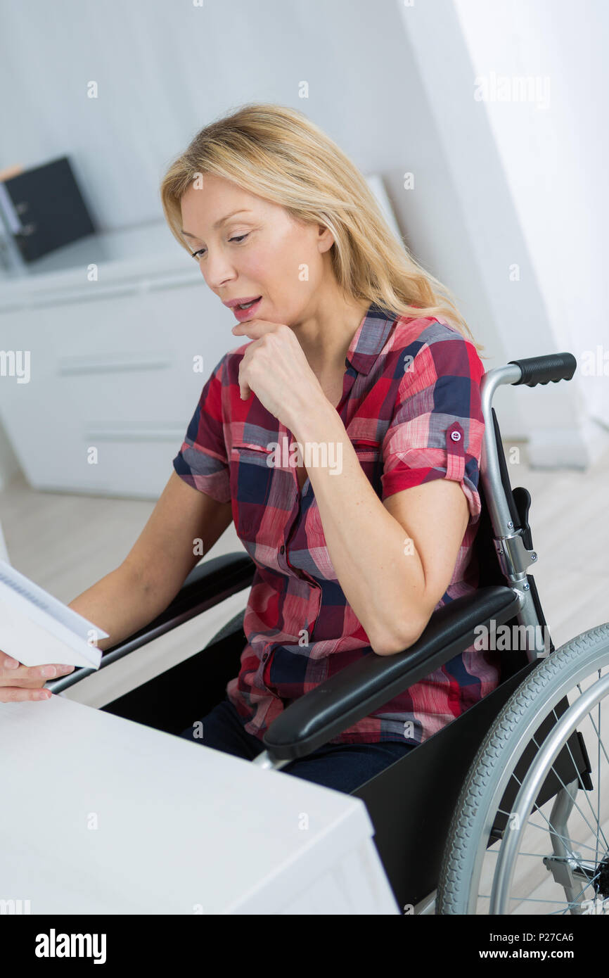 pleasant disabled woman sittign in the wheelchair at home Stock Photo