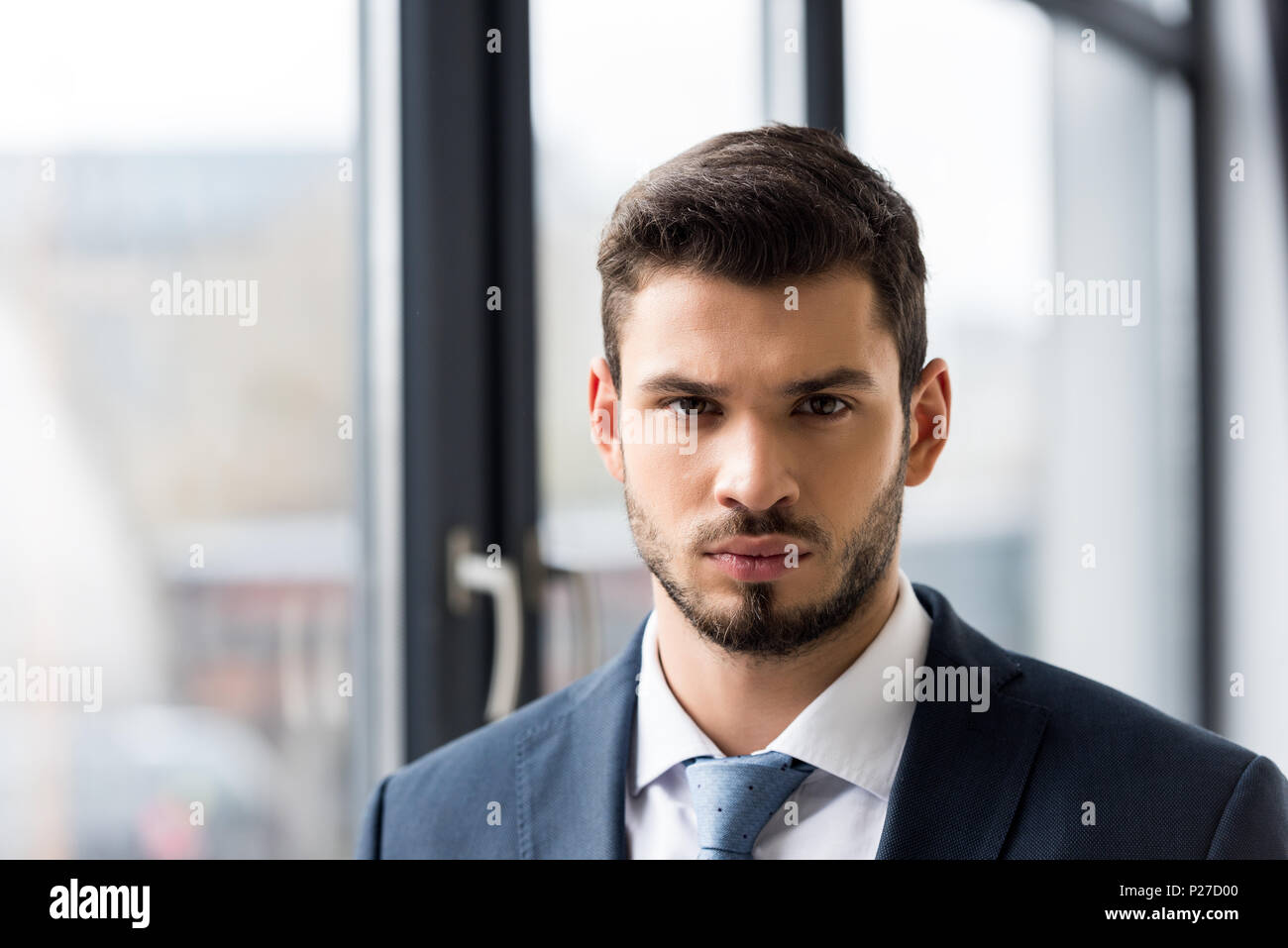 portrait of handsome young businessman in formal wear looking at camera ...