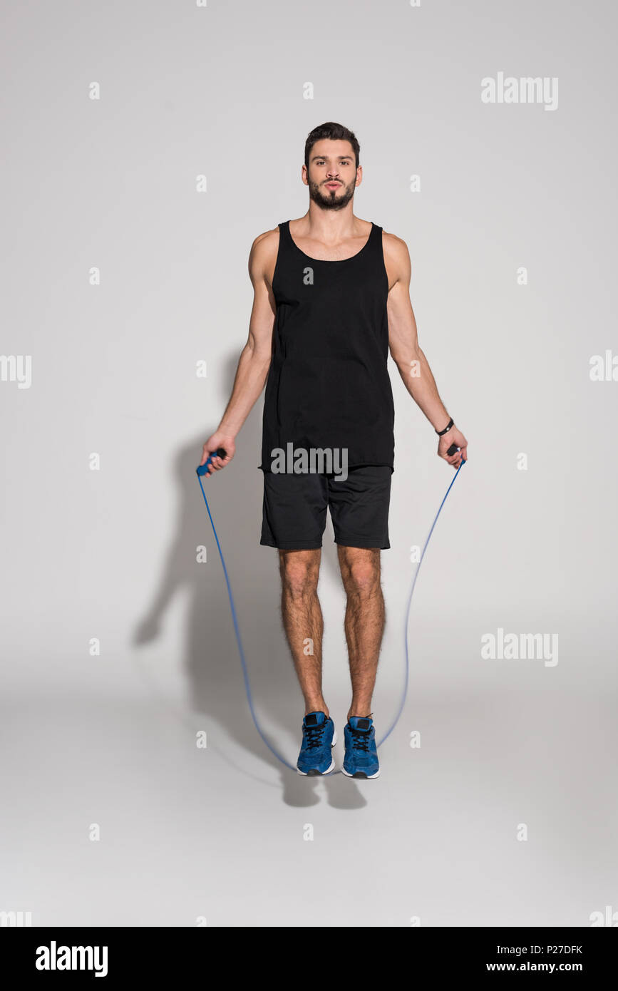 sportive young man jumping with rope on white Stock Photo