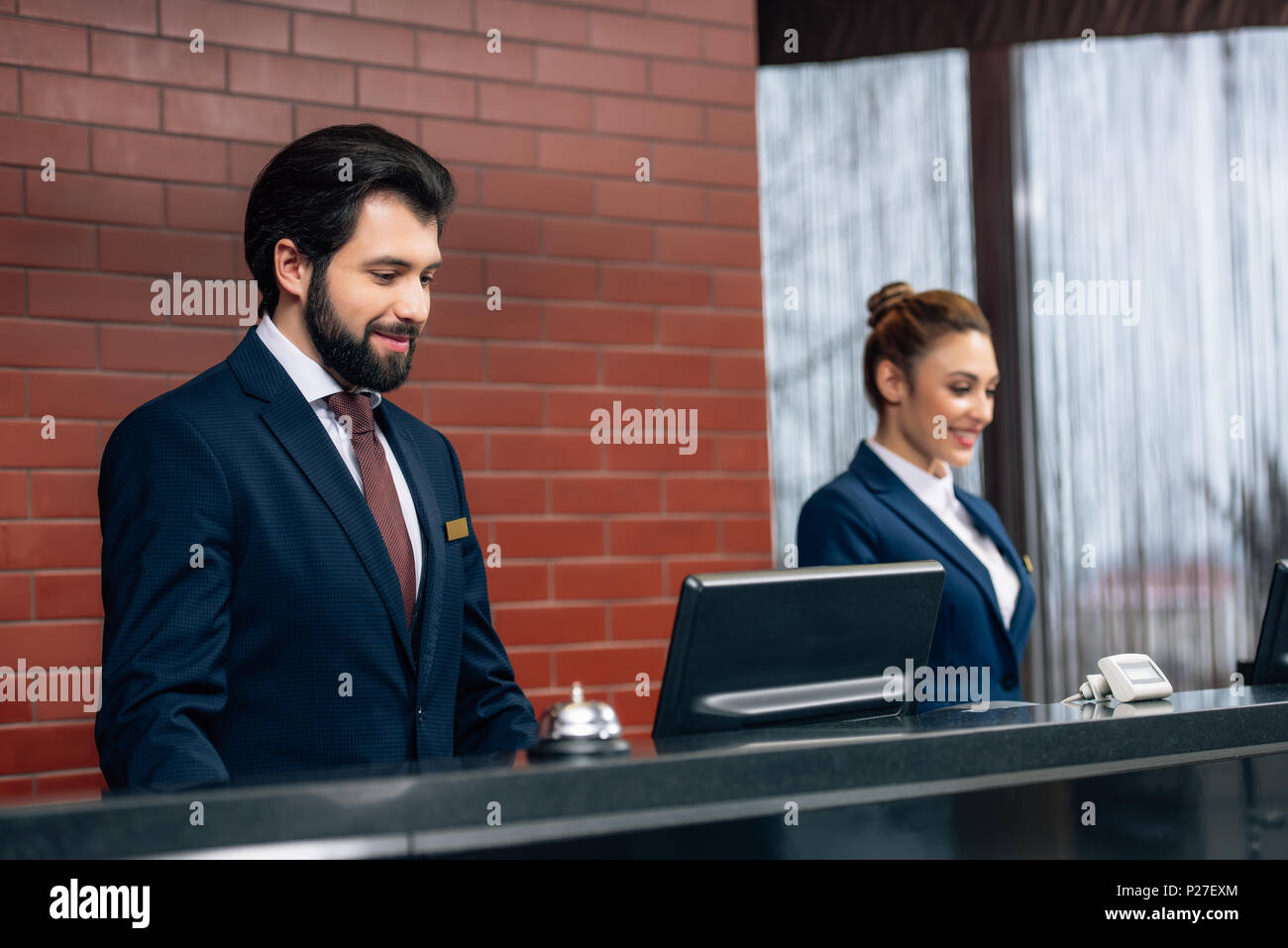 hotel receptionists working with computers together at counter Stock Photo