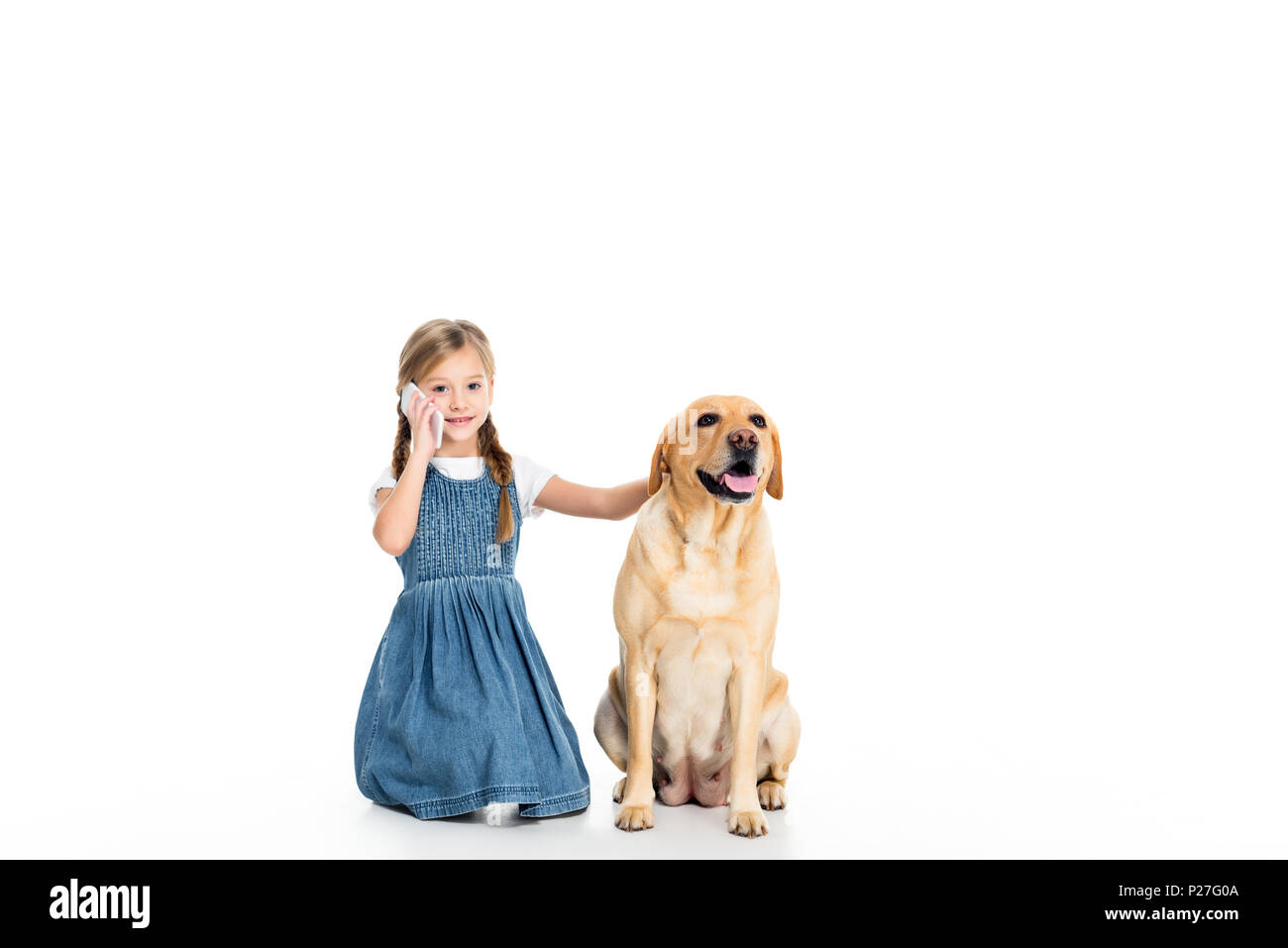 adorable kid sitting with dog while talking on smartphone, isolated on white Stock Photo