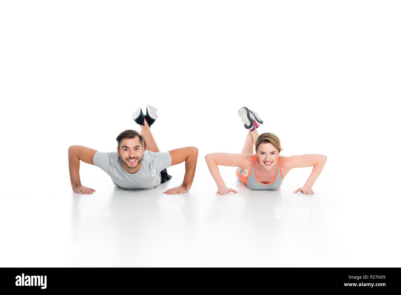 cheerful athletic couple doing push ups together isolated on white Stock Photo