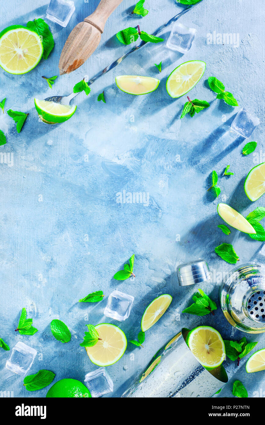 Fresh mojito cocktail ingredients, mint, lime and ice cubes on a gray stone background. Shaker and bar accessories flat lay. Summer drink concept with Stock Photo