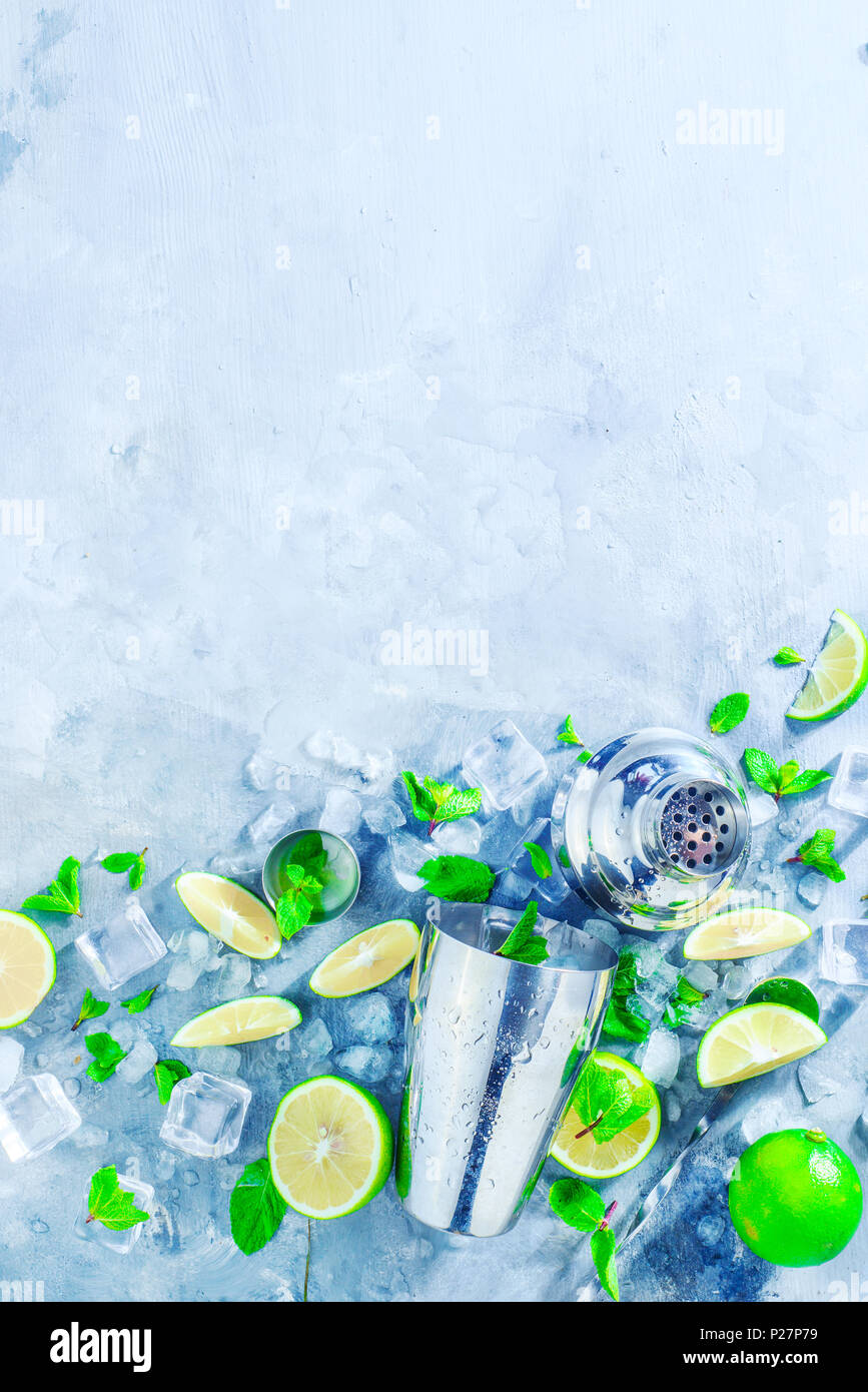 Shaker and bar accessories flat lay. Fresh mojito cocktail ingredients, mint, lime and ice cubes on a gray stone background. Summer drink concept with Stock Photo