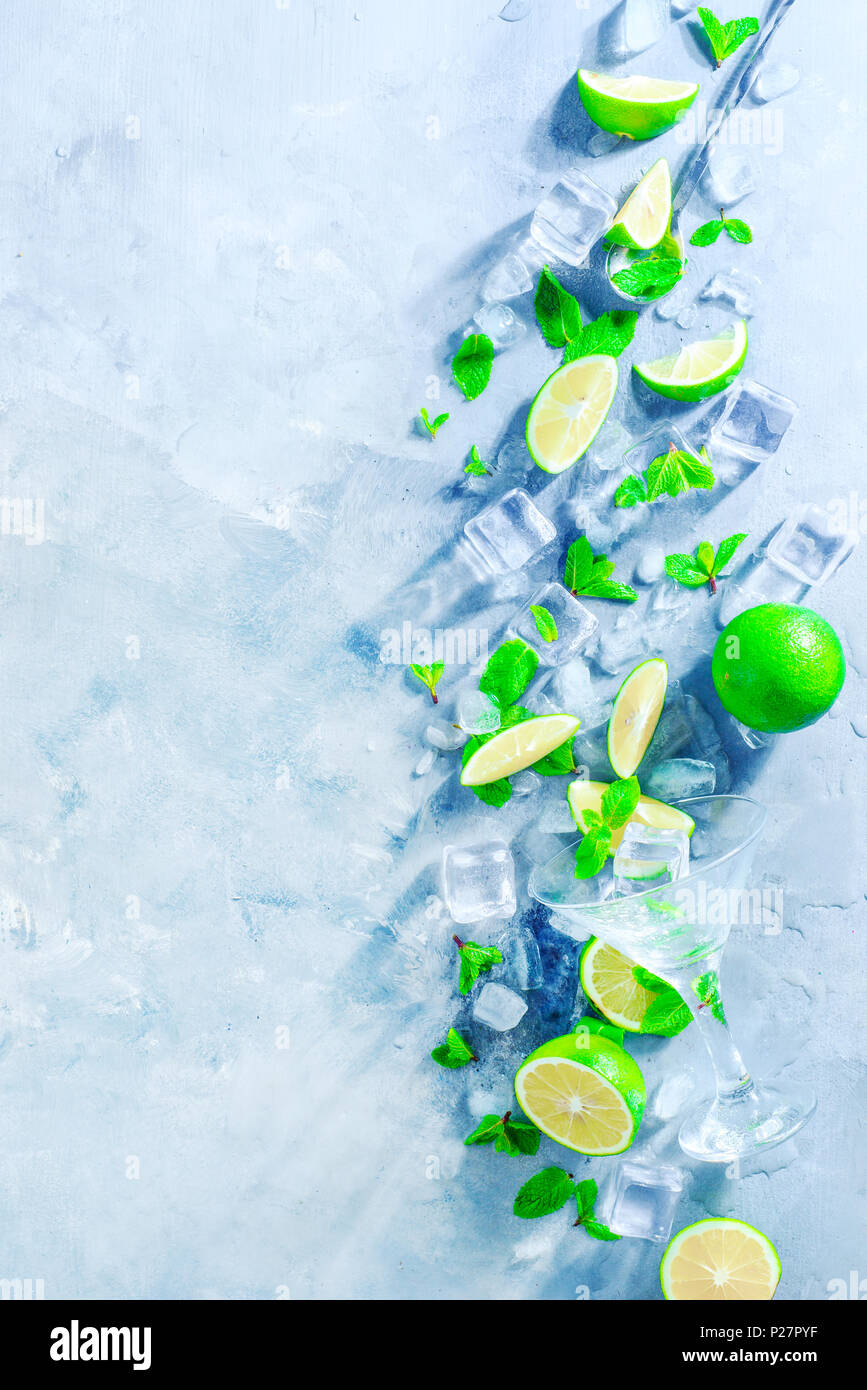 Mint, lime and ice cubes on a gray stone background with copy space. Making summer drinks flat lay. Sunlight and refreshment concept. Stock Photo