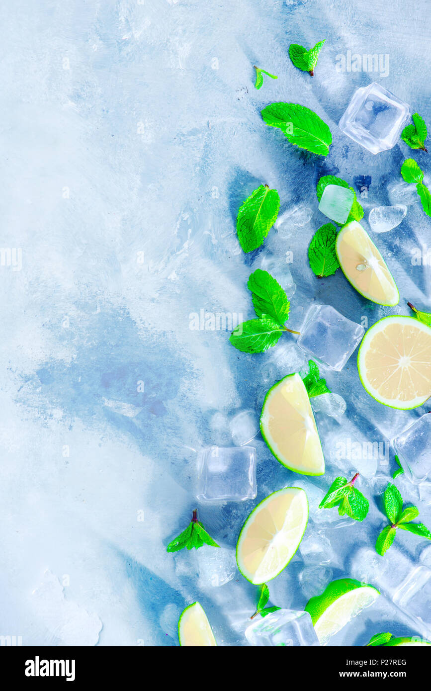 Mint, lime and ice cubes on a gray stone background with copy space. Making summer drinks flat lay. Sunlight and refreshment concept. Stock Photo