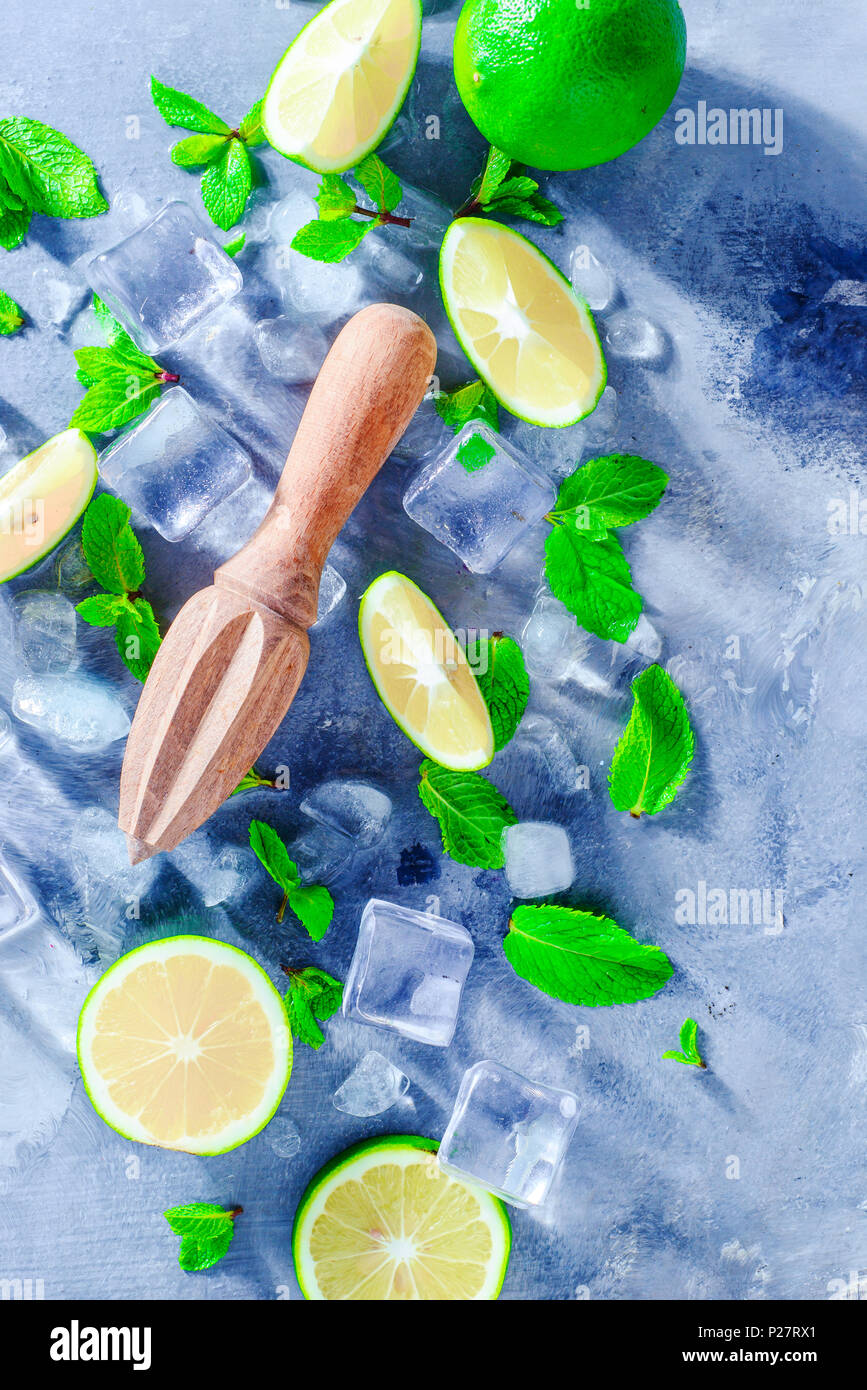 Lemon reamer or juicer with mint, lime and ice cubes. Mojito cocktail ingredients on a gray stone background with copy space. Summer drink concept sun Stock Photo