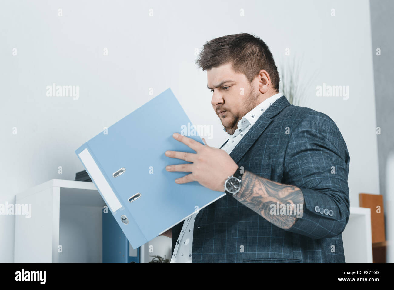 overweight businessman in suit working with documents in folders Stock Photo