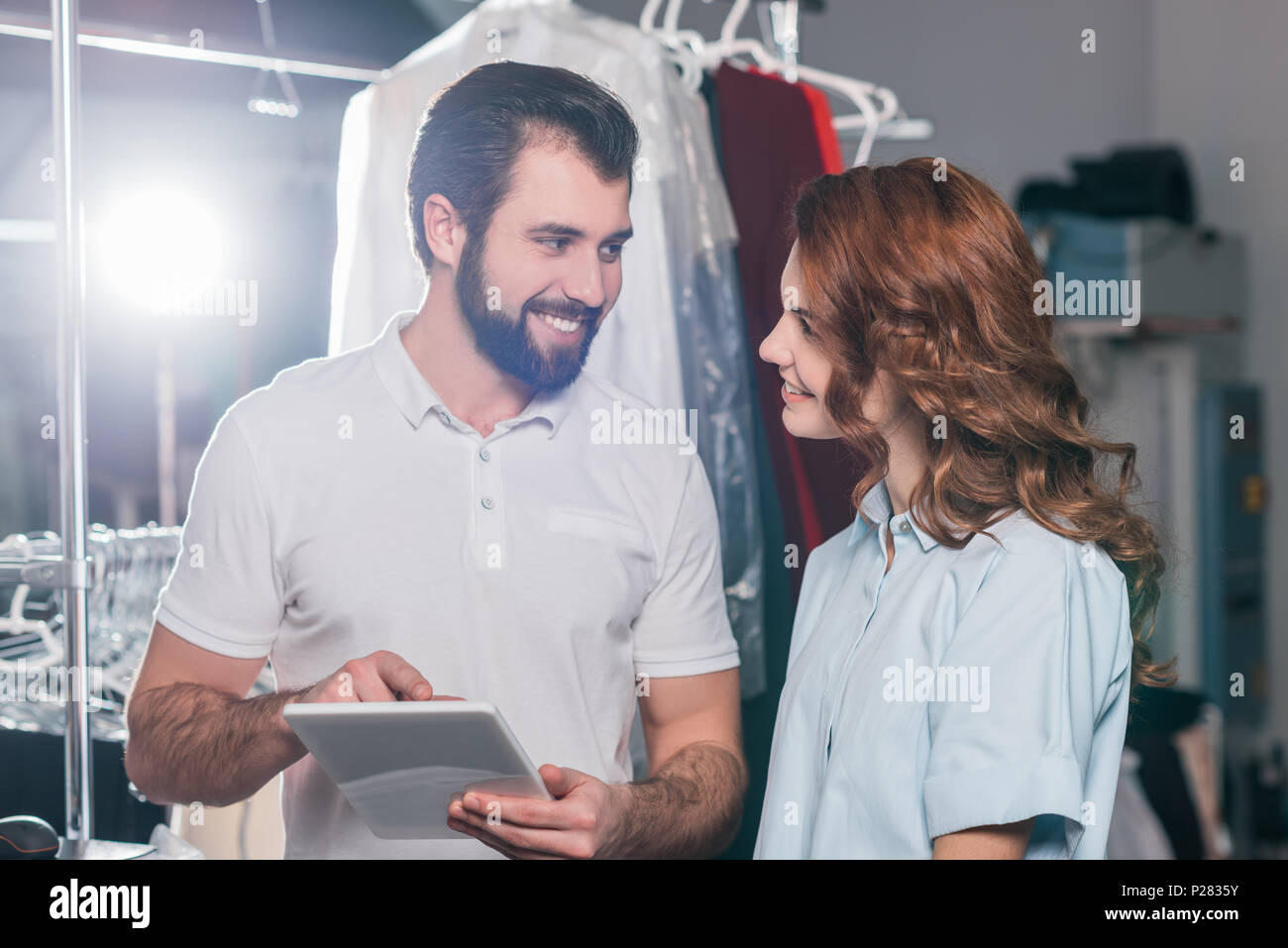 smiling dry cleaning workers using tablet together Stock Photo
