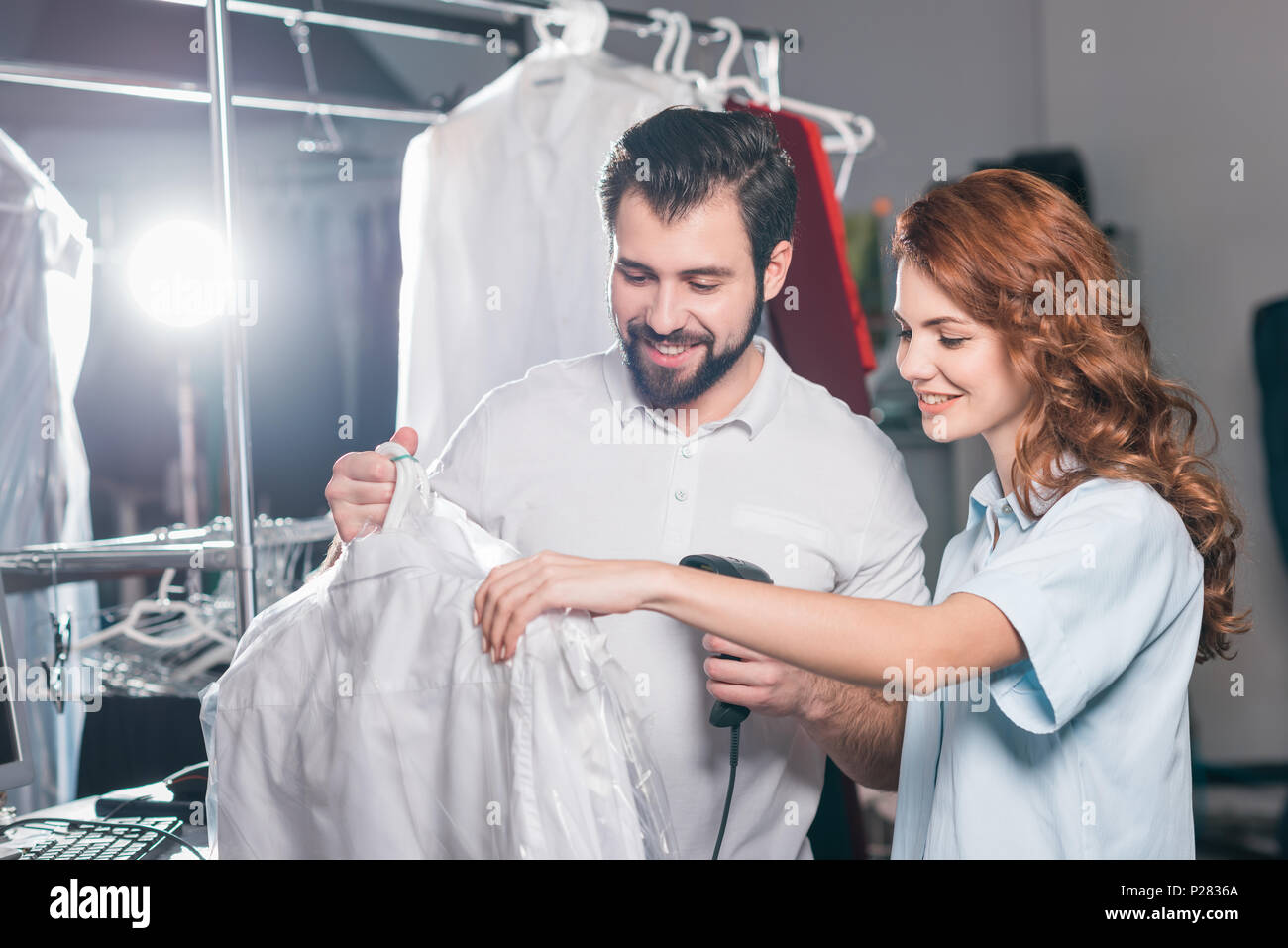 young dry cleaning workers scanning barcode on bag with shirt Stock