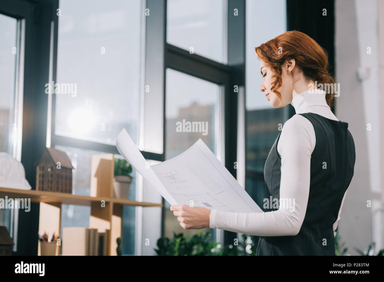 beautiful female architect looking at blueprint in modern office Stock ...